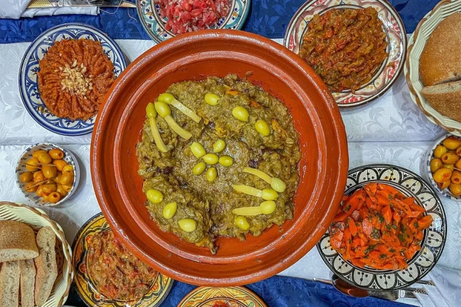 Guests enjoying a Berber cooking class in Imlil Valley, learning to prepare traditional Moroccan Tagine and Couscous with a local chef