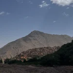 Panoramic view of Imlil village and the starting point of the Mt Toubkal trek, with terraced fields and trekkers preparing for the ascent.