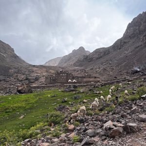 High-altitude mountain refuge at 3200m on Mount Toubkal, surrounded by rocky slopes and early-season snow patches, used as the main base camp for trekkers. High-altitude mountain refuge at 3200m on Mount Toubkal, surrounded by rocky slopes and early-season snow patches, used as the main base camp for trekkers.