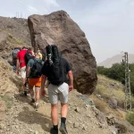 Trail from Imlil toward Sidi Chamharouch showing rocky paths, terraces, and hikers starting their Mount Toubkal 2 day trek.
