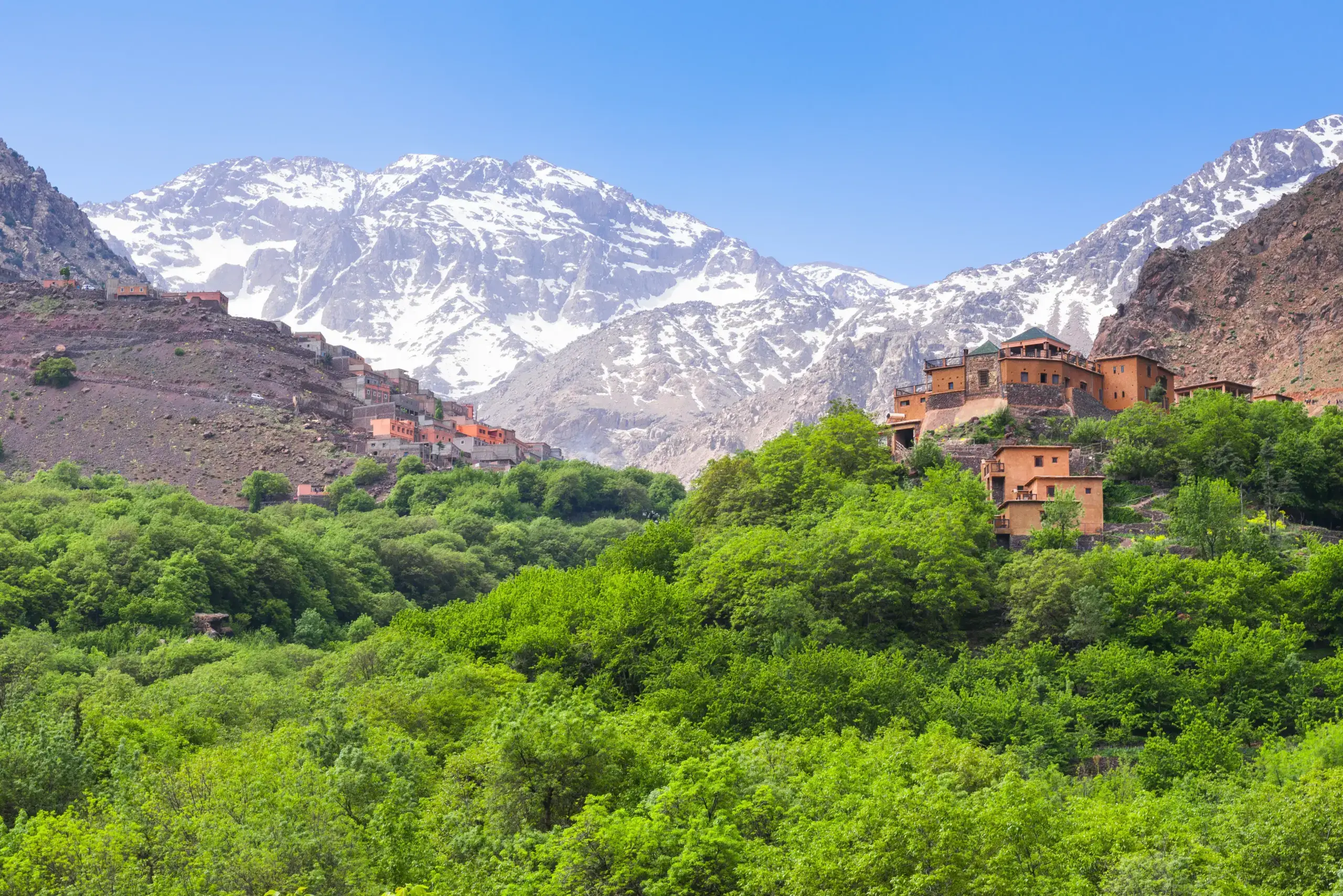 Early morning light in Imlil Valley with terraces, orchards, and traditional stone houses under soft mountain shadows.