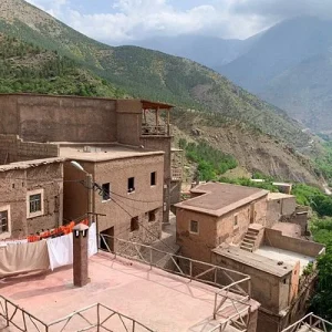 Local residents walking through narrow lanes in Imlil village Morocco, with a mule passing between terraced fields. Local residents walking through narrow lanes in Imlil village Morocco, with a mule passing between terraced fields.